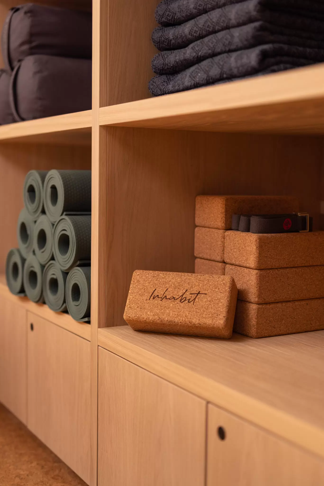 yoga cork brick and green yoga mats stacked on shelf